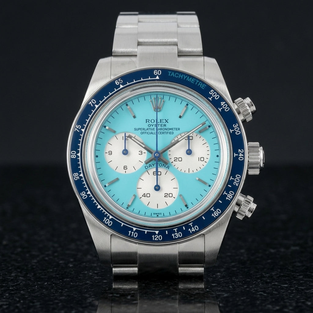 Steel chronograph with a turquoise dial on its steel bracelet, worn on the wrist below a dark suit cuff