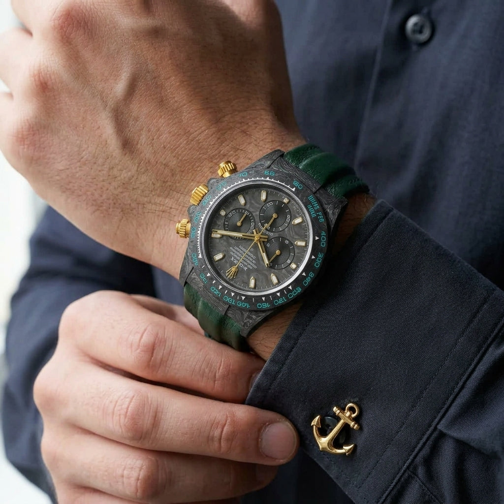 Forged-carbon chronograph with a marbled carbon dial, gold fittings and turquoise bezel numerals on the wrist as a shirt cuff is fastened