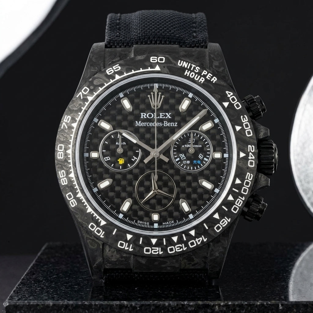 Black forged carbon chronograph on its black woven canvas strap, worn on the wrist below a navy suit cuff