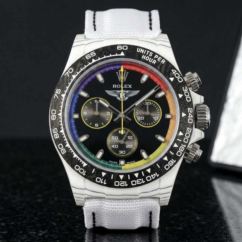White carbon rainbow-ring chronograph on its white woven canvas strap, worn on the wrist below a navy suit cuff