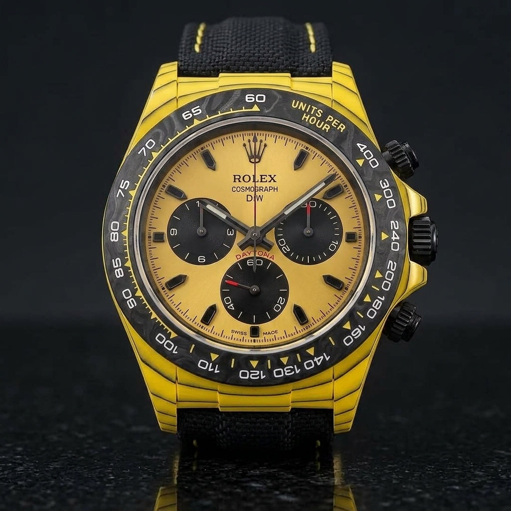 Yellow carbon chronograph on its black canvas strap with yellow stitching, worn on the wrist below a navy suit cuff