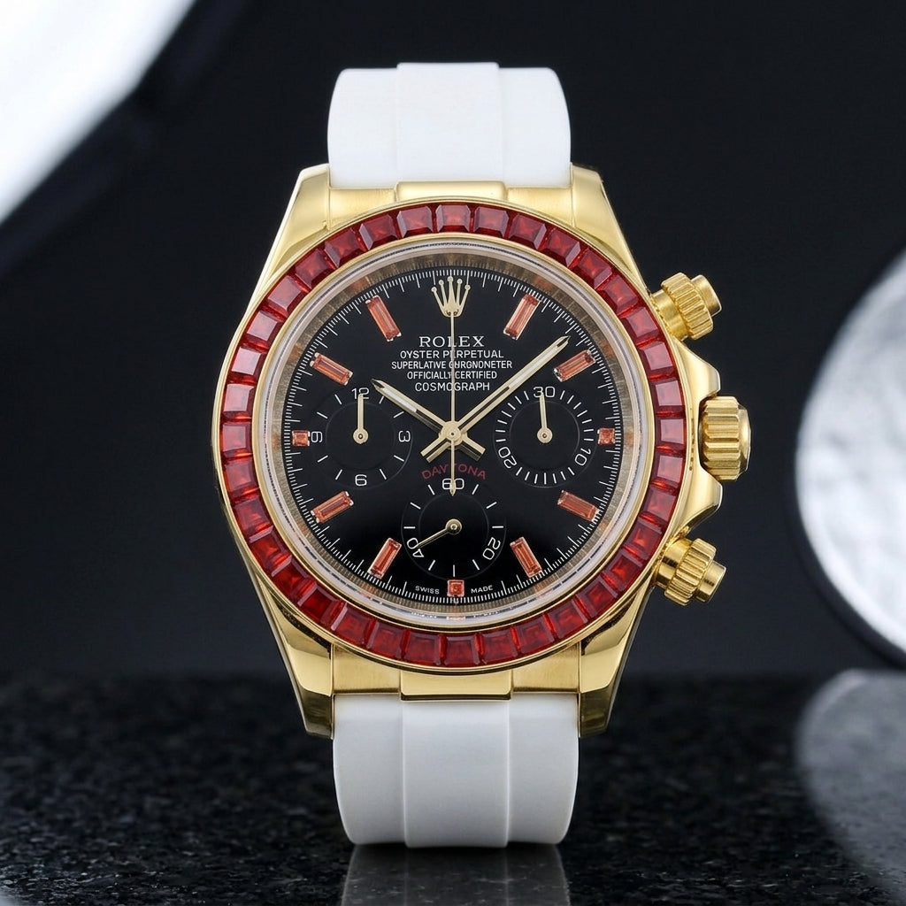 Gold-tone chronograph with a red stone bezel on its white rubber strap, worn on the wrist below a dark suit cuff