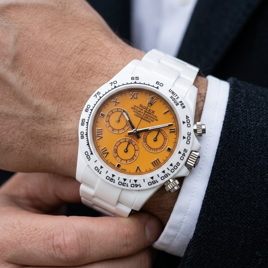 White ceramic chronograph with an orange dial and black Roman numerals on the wrist as a shirt cuff is fastened