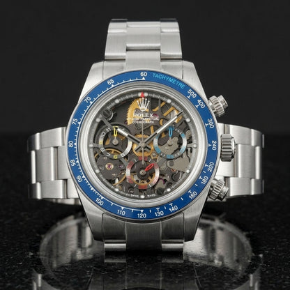 Steel skeleton chronograph with a glossy blue tachymetre bezel, upright on polished black granite