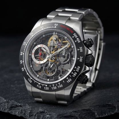 Steel skeleton chronograph at a three-quarter angle on dark slate, the black crown and pushers against the polished flank
