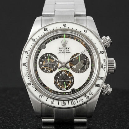 Steel chronograph with a milky white dial, three skeleton counters and neon-green accents, upright on polished marble