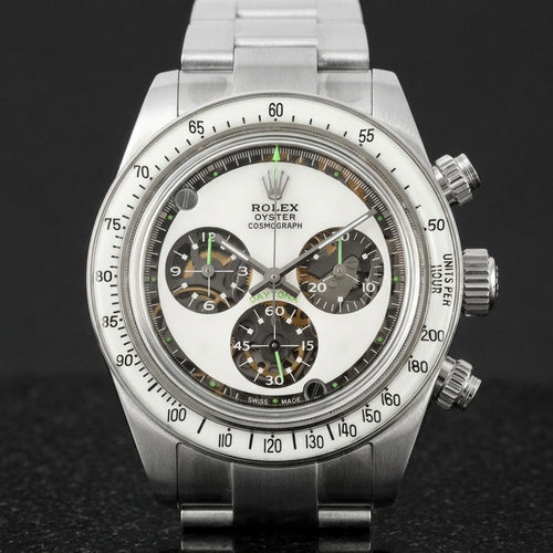 Steel chronograph with a milky white dial, three skeleton counters and neon-green accents, upright on polished marble