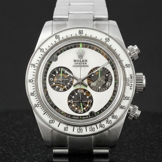 Steel chronograph with a milky white dial, three skeleton counters and neon-green accents, upright on polished marble