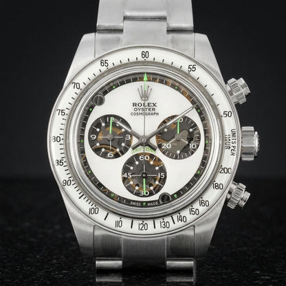 Steel chronograph with a white dial and green accents on the wrist below a dark suit cuff