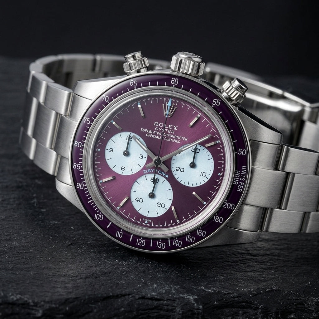 Steel chronograph at a three-quarter angle on dark slate, the plum bezel beside the screw-down crown and pushers