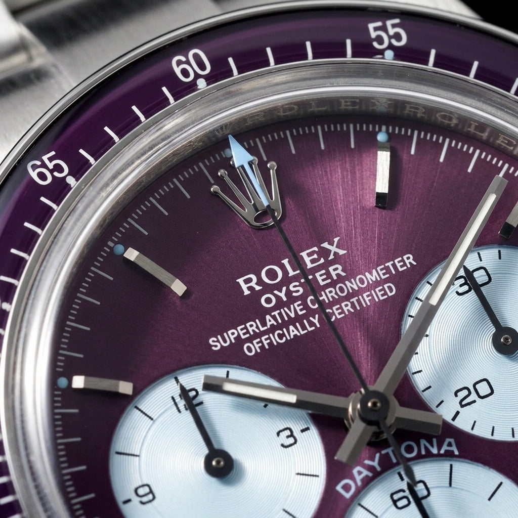 Macro of the plum sunburst dial with ice-blue counters, steel baton markers and light-blue luminous dots