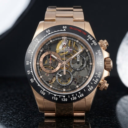 Rose gold skeleton chronograph with a black tachymeter bezel and an open-worked dial, upright on polished black granite