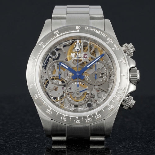 Steel skeleton chronograph with a grey open-worked dial and blue hands, upright on polished black granite