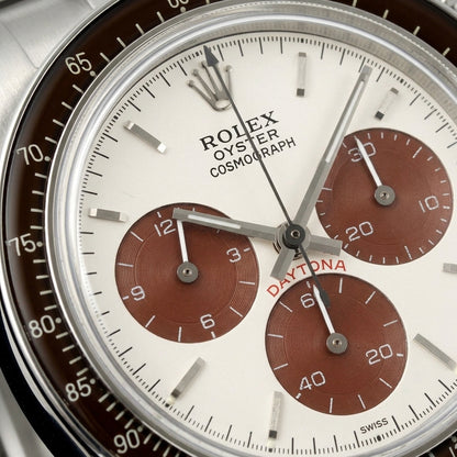 Macro of the warm white dial with three reddish-brown grooved counters and the cream-printed brown bezel