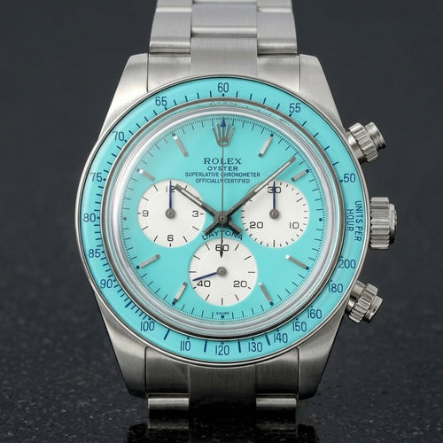 Steel chronograph with a turquoise dial, turquoise bezel and silver-white counters, upright on polished marble