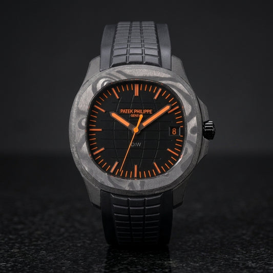 Black forged-carbon grid-dial watch with orange batons and a black rubber strap, upright on polished black granite