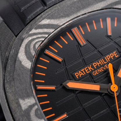 Macro of the matte black globe-grid dial with orange batons, orange minute strokes, orange hands and the date window at three