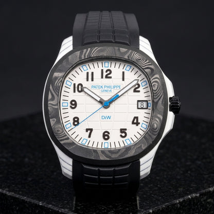 White carbon grid-dial watch with a black marbled bezel and blue hour markers on a black rubber strap, upright on polished black granite