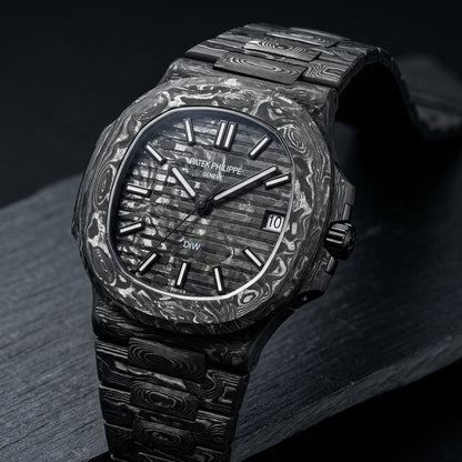 All-carbon sports watch at a three-quarter angle on dark slate, black and silver-white marbling across case, dial and bracelet