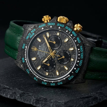 Forged-carbon chronograph with gold hands at a three-quarter angle on dark slate