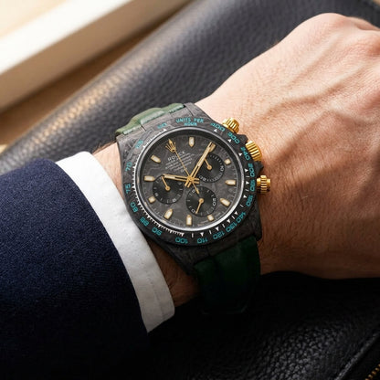 Forged-carbon chronograph on a dark green leather strap, worn under a cuff