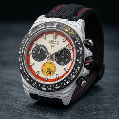 White forged carbon chronograph at a three-quarter angle on dark slate, fine dark layer lines along its flank beside the black pushers