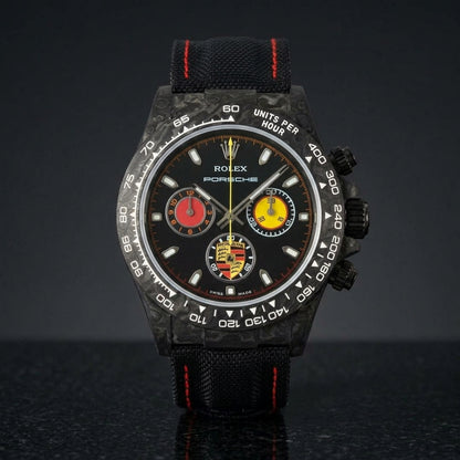Black forged-carbon chronograph on a red-stitched strap worn under a suit cuff
