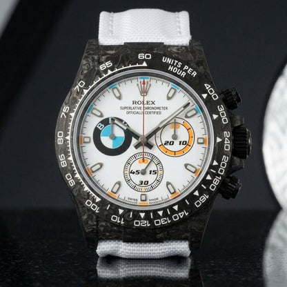 Black forged-carbon chronograph on a white strap worn under a suit cuff