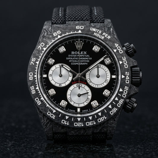 Black forged carbon chronograph with a black dial, silver counters and clear stone hour markers, upright on polished black granite