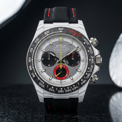 White forged carbon chronograph with a black bezel, a grey and white dial and a red counter at six, upright on polished black granite