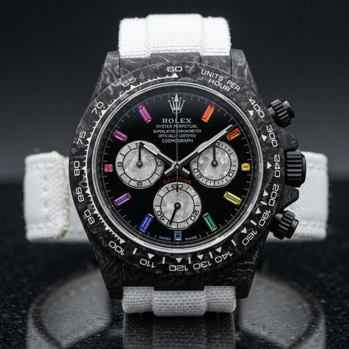 Black forged carbon chronograph with a carbon tachymeter bezel and a black dial with rainbow stone markers, upright on polished black granite