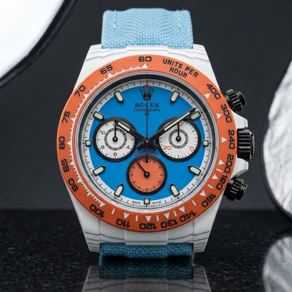 White carbon chronograph on its light sky-blue canvas strap, worn on the wrist below a navy suit cuff