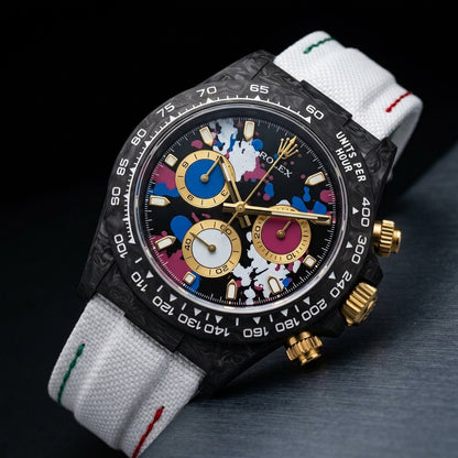 Black forged-carbon chronograph with gold pushers at a three-quarter angle on dark slate