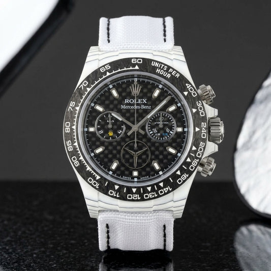 White forged carbon chronograph with a black bezel, a woven carbon-fibre dial and a three-pointed star emblem, upright on polished black granite