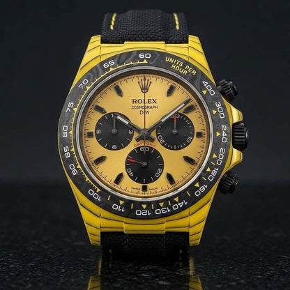 Yellow carbon chronograph on its black canvas strap with yellow stitching, worn on the wrist below a navy suit cuff