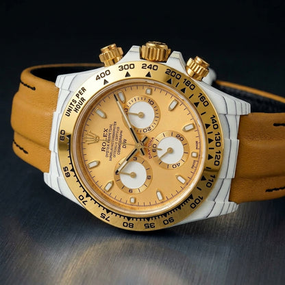 White-cased chronograph with gold bezel at a three-quarter angle on dark slate