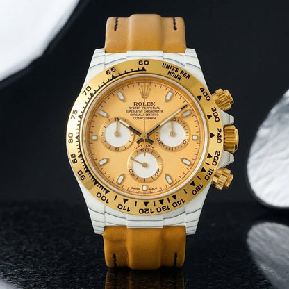White-cased chronograph on a tan leather strap, worn under a cuff
