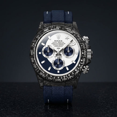 Forged-carbon chronograph with a white and navy dial and a star at twelve, on dark stone