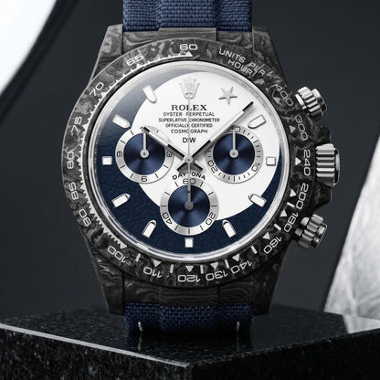 Forged-carbon chronograph on a navy woven strap, worn under a cuff