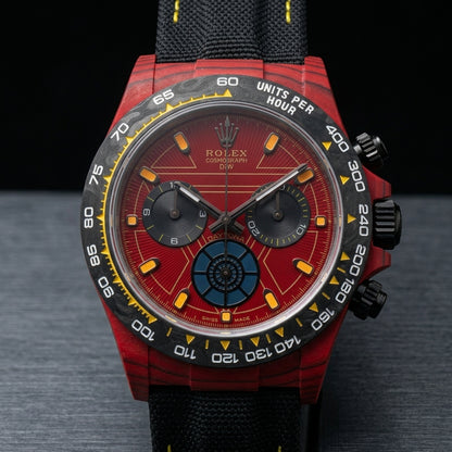 Red forged-carbon chronograph at a three-quarter angle on dark slate, black pushers to the right