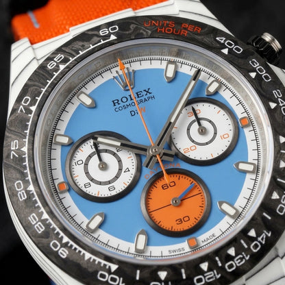 Macro of the sky-blue and white dial with white counters at three and nine and a solid orange counter at six