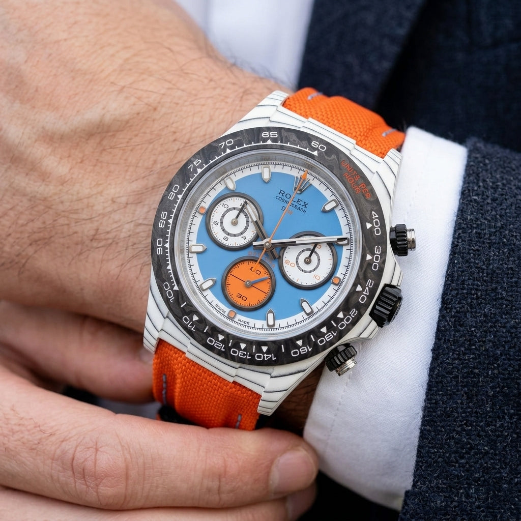 White carbon chronograph with a sky-blue dial and an orange counter on the wrist as a shirt cuff is fastened