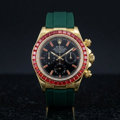 Gold chronograph with a red stone bezel and a black dial on a dark green rubber strap, upright on polished black granite