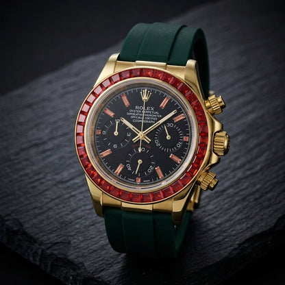 Gold chronograph at a three-quarter angle on dark slate, the fluted gold crown and pushers beside the ring of red baguette stones