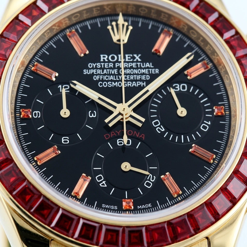 Macro of the black dial with orange stone markers and three black counters inside the ring of red baguette-cut stones