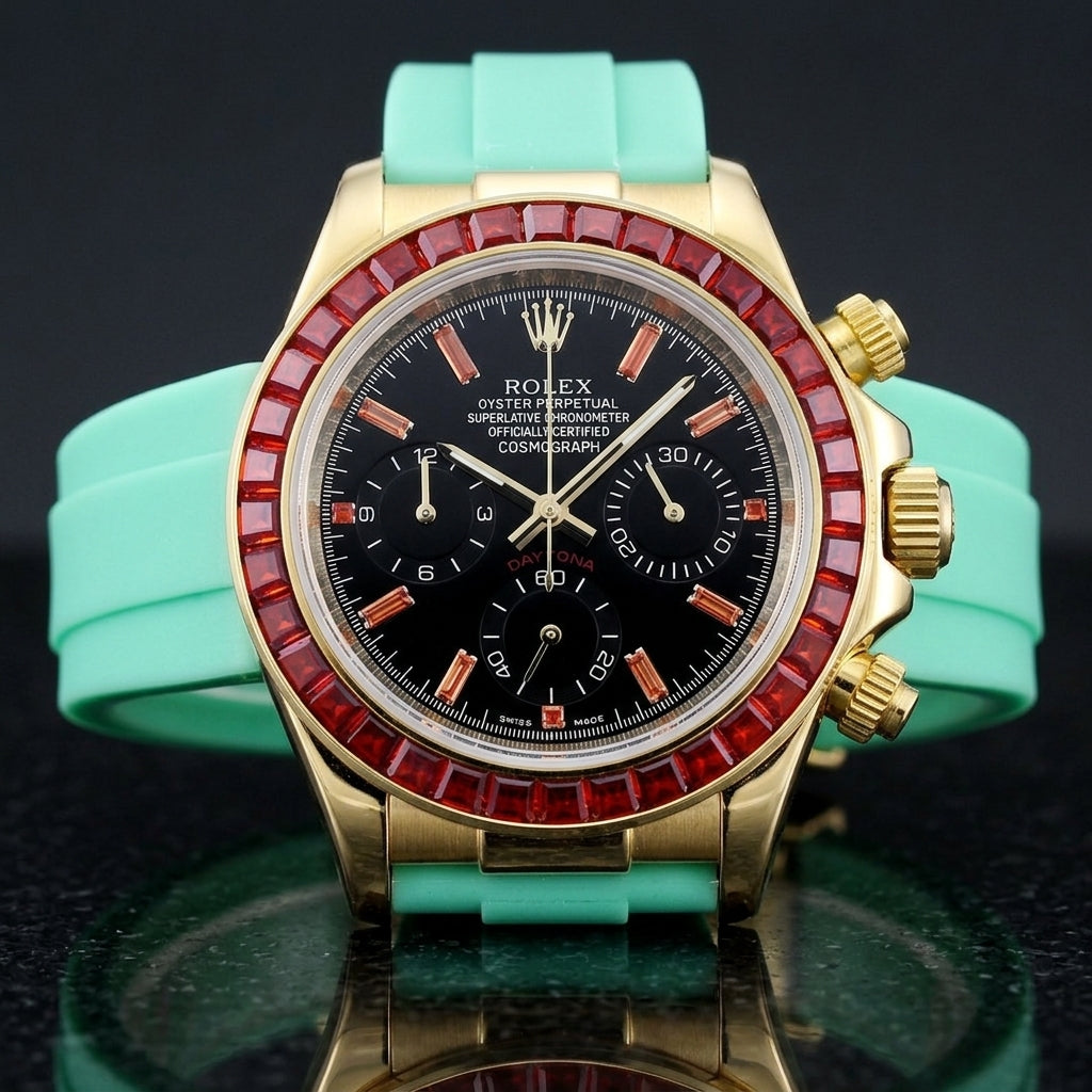 Gold chronograph with a red stone bezel on its mint-green rubber strap, worn on the wrist below a dark suit cuff