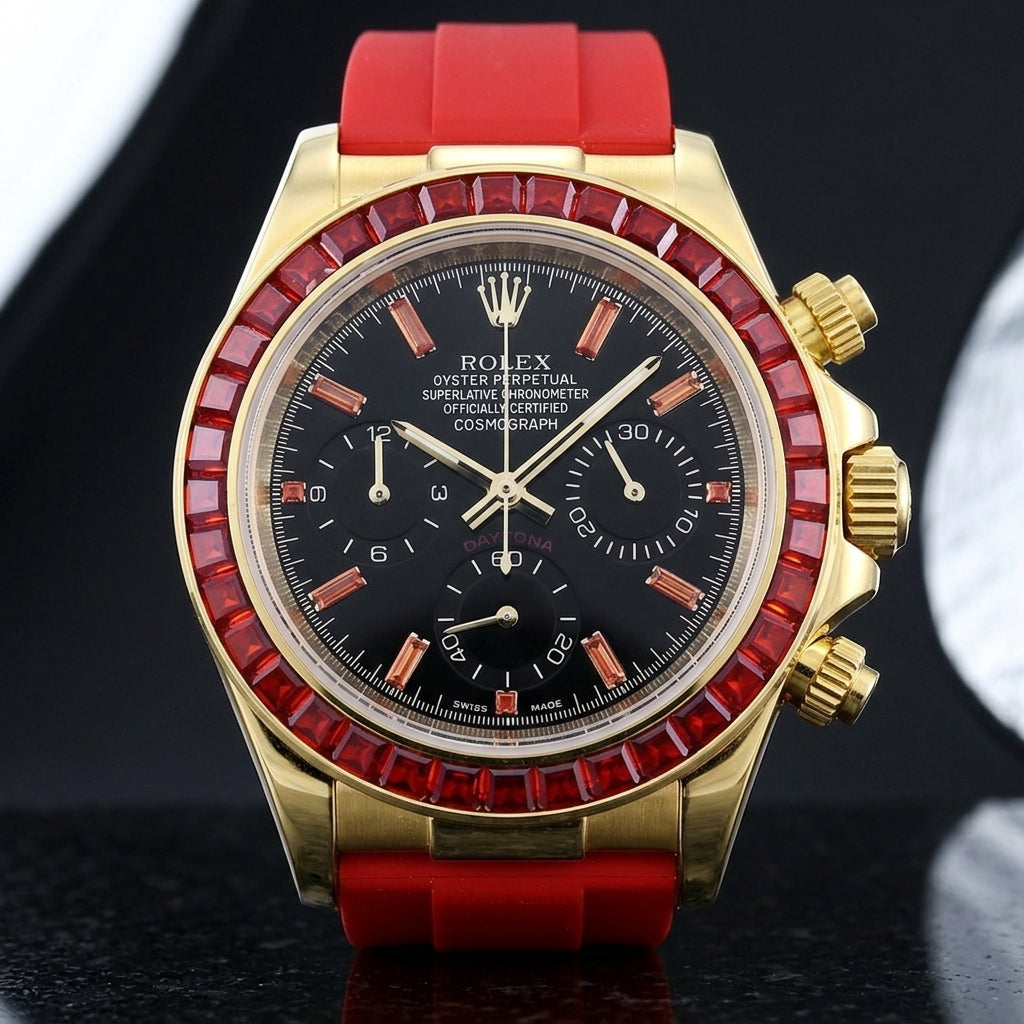 Gold-tone chronograph with a red stone bezel on its red rubber strap, worn on the wrist below a dark suit cuff