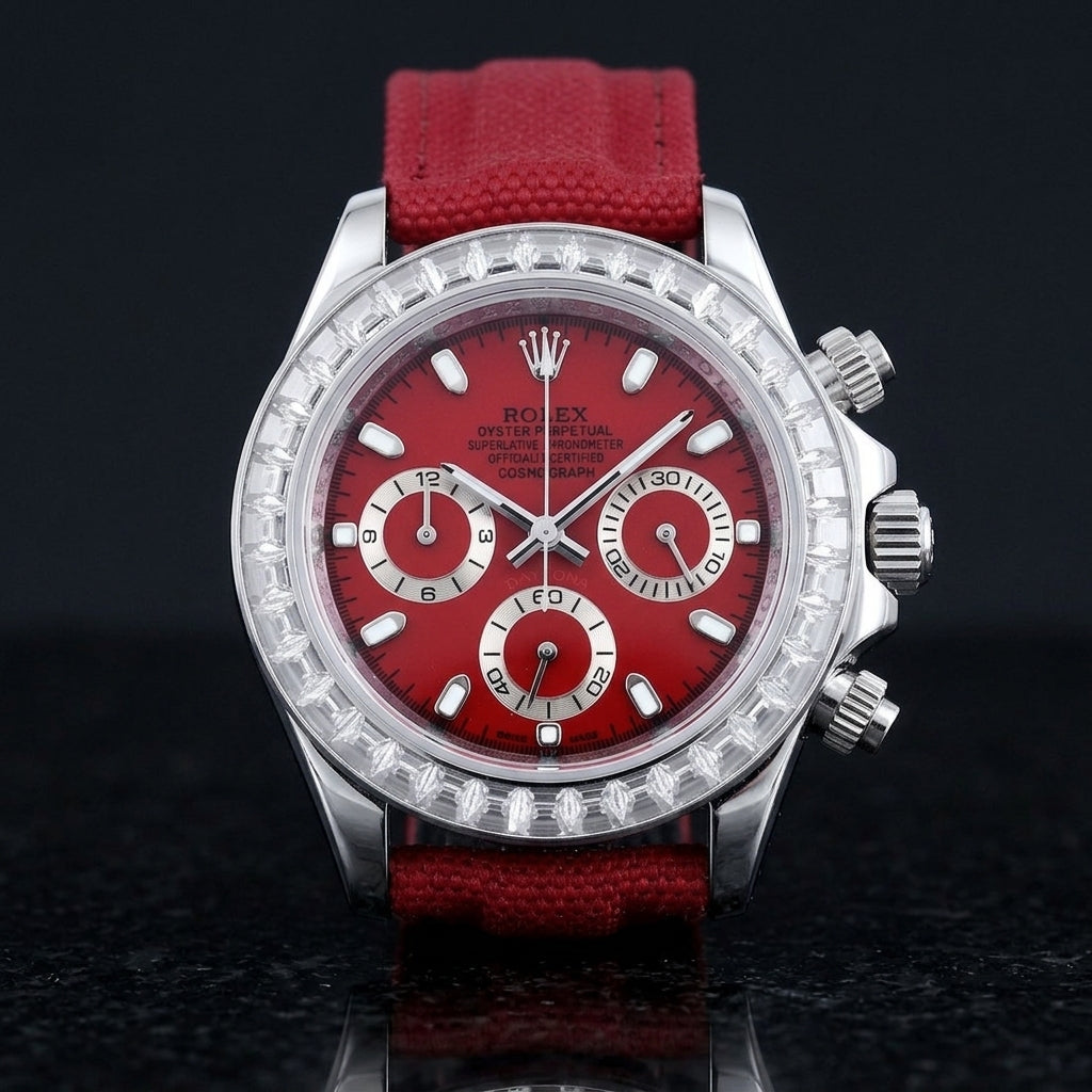Steel chronograph with a red dial on its red canvas strap, worn on the wrist below a dark suit cuff