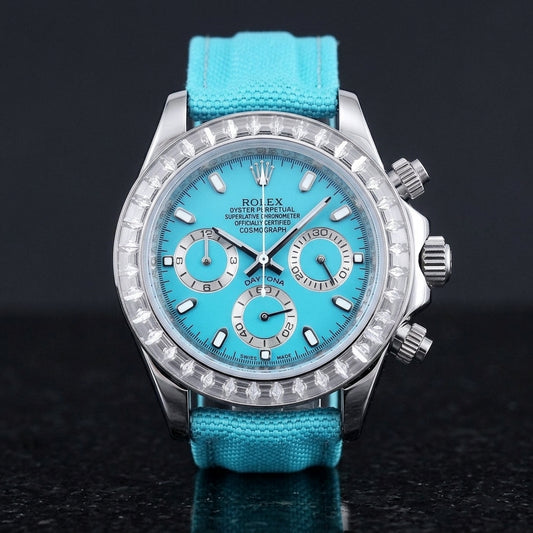 Steel chronograph with a turquoise dial, three silver counters and a clear baguette-stone bezel, upright on polished black granite