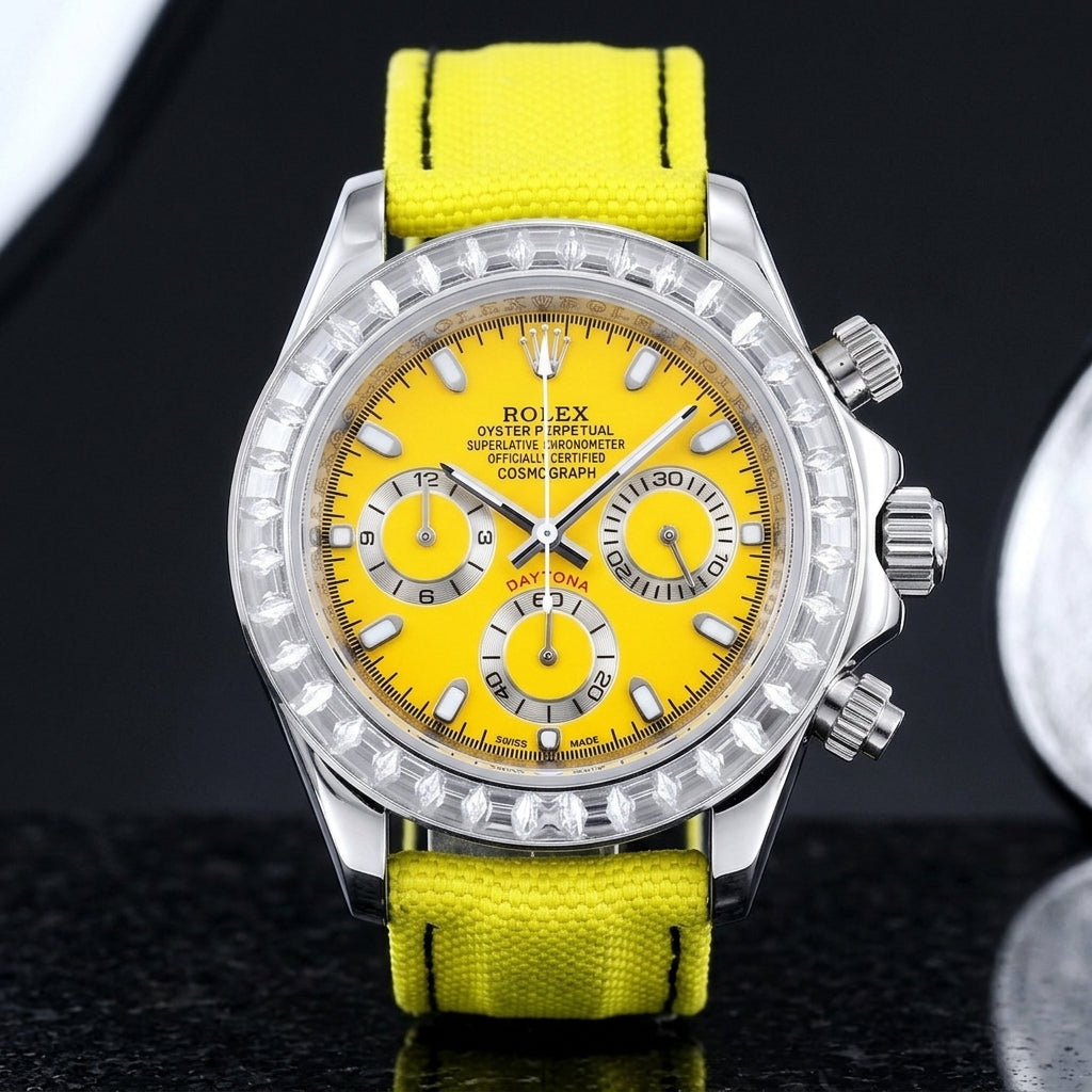 Steel chronograph with a yellow dial on its lemon-yellow canvas strap, worn on the wrist below a dark suit cuff